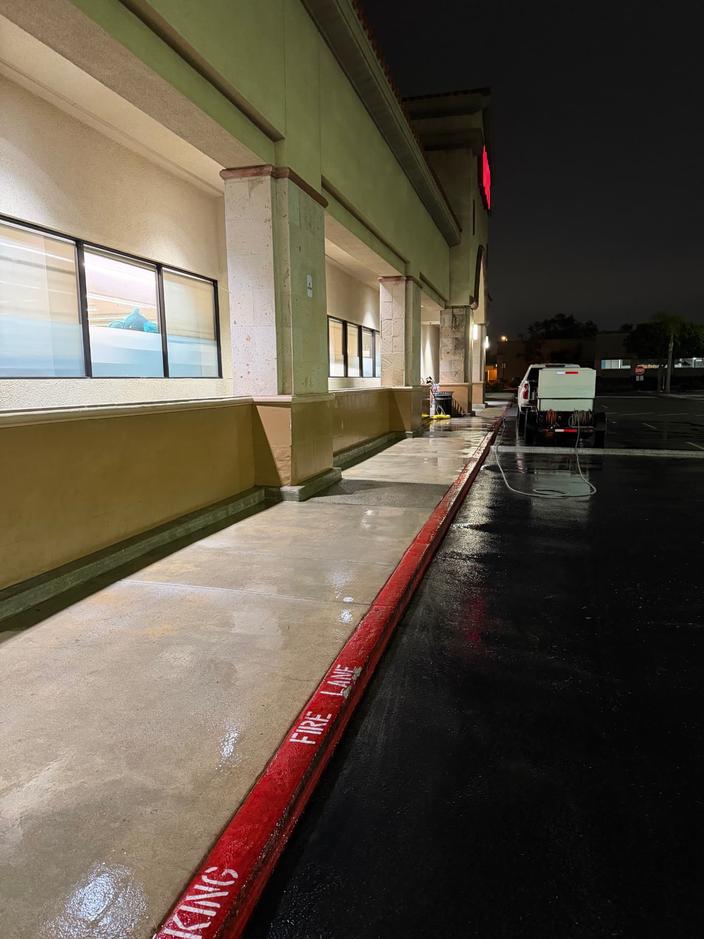 Freshly pressure washed shopping center sidewalk and fire lane at night